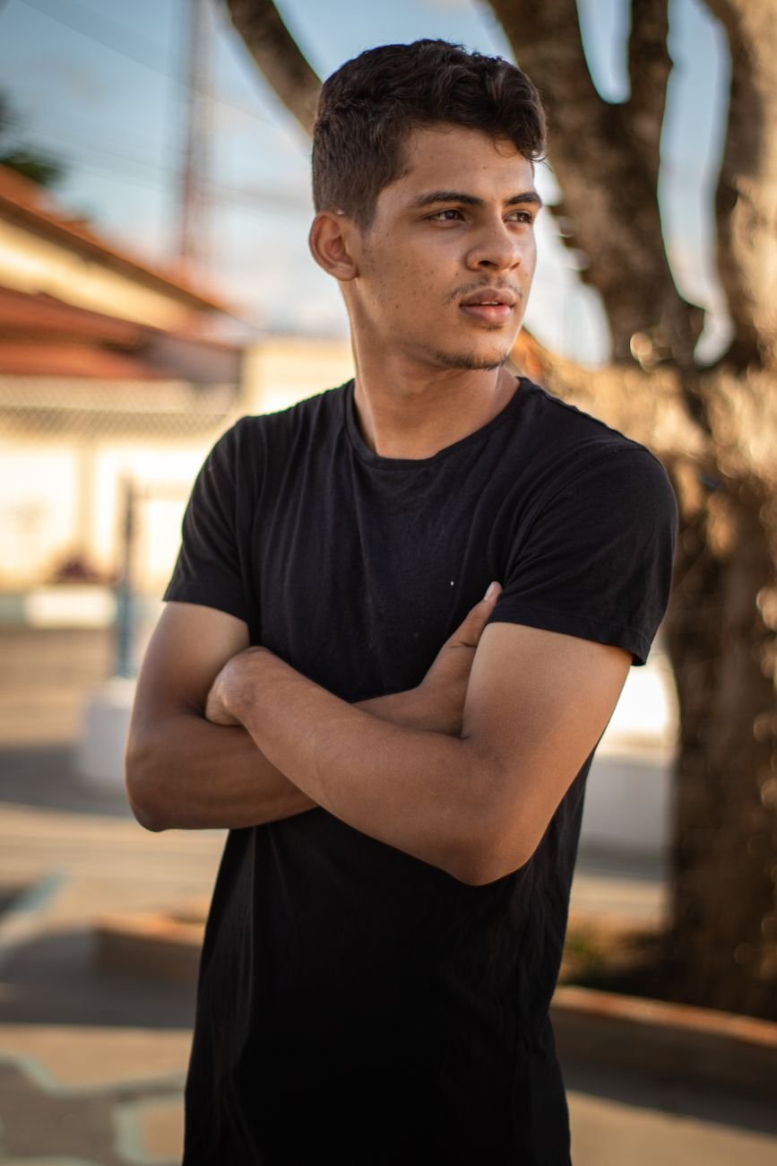 Portrait of a young man standing outdoors with a confident pose.